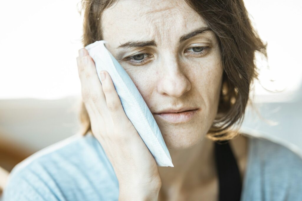 Woman holding a cold pack against her cheek to ease a toothache